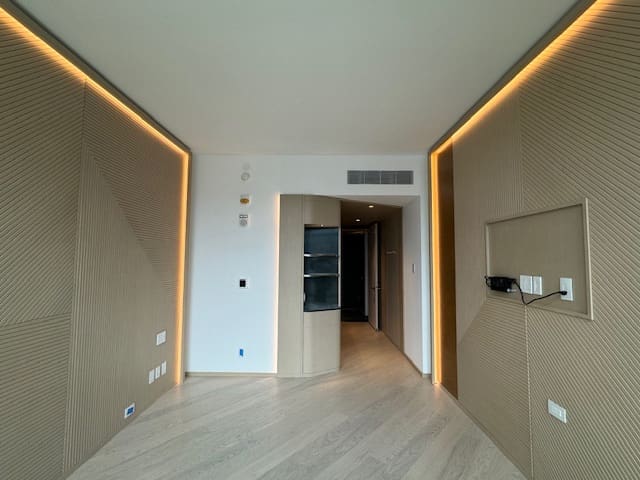 Modern empty room with wooden flooring and warm lighting.