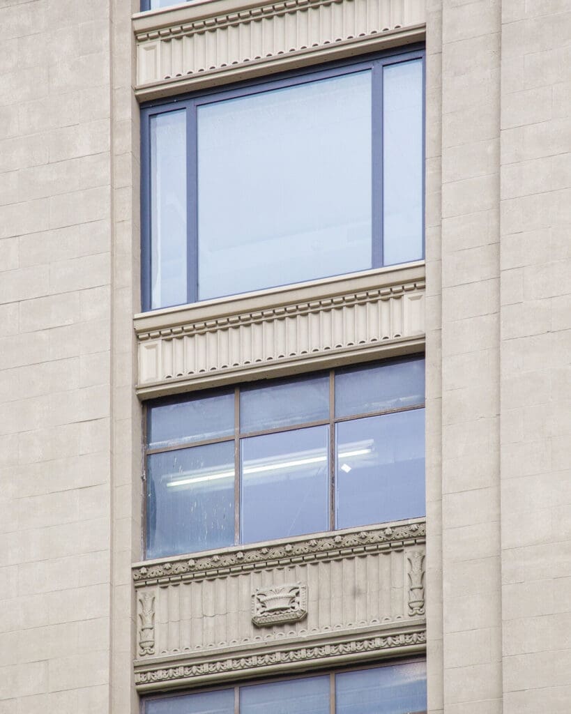 A building with two windows and one has a light blue sky in the background.