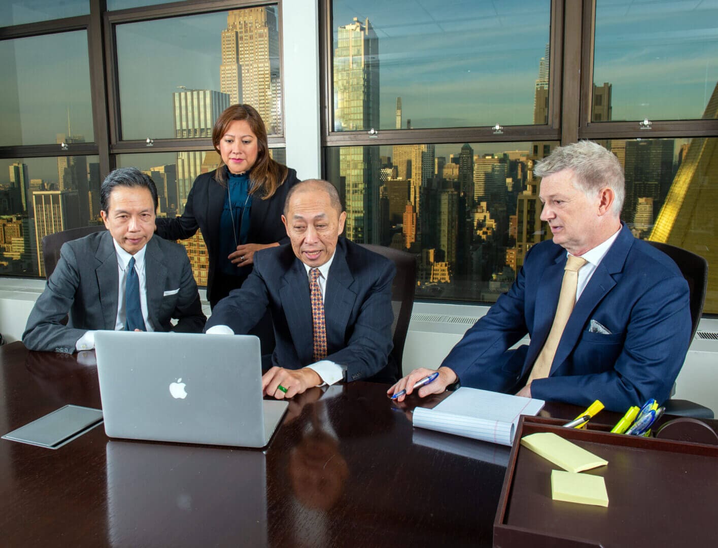 A group of people sitting at a table with laptops and talking