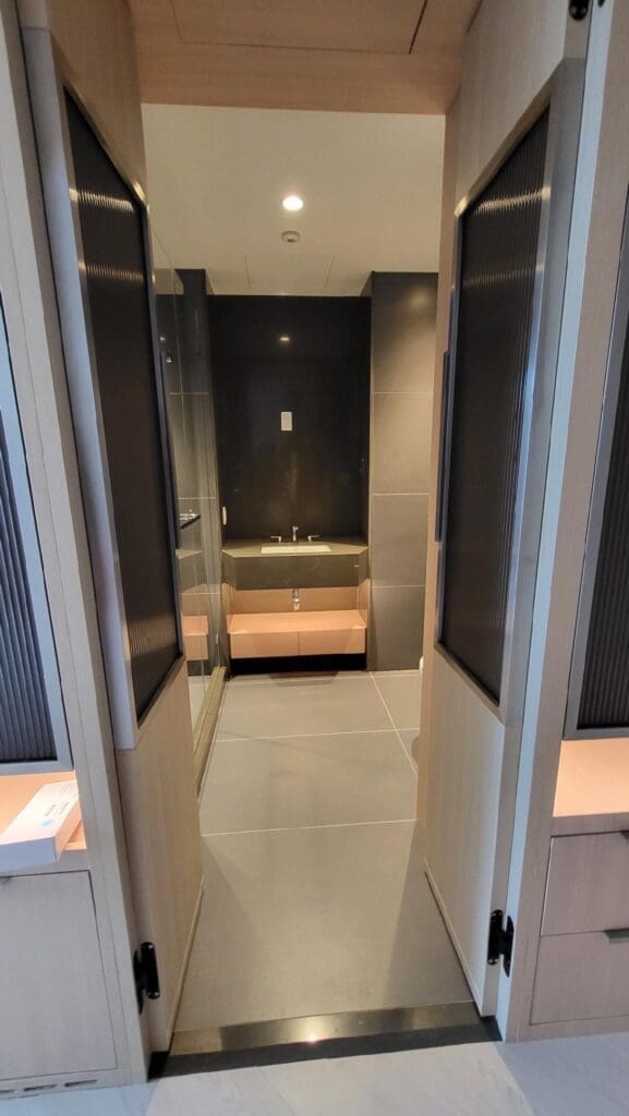 Modern bathroom with a sleek black and gray design and a wooden bench.