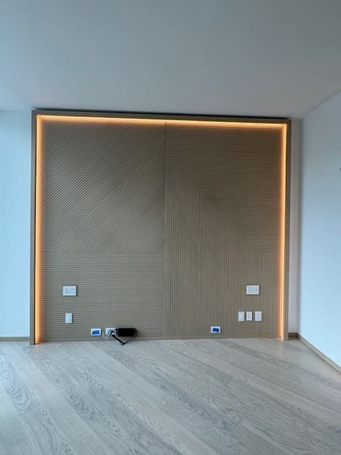 Minimalist empty room with a built-in wooden frame and outlets.